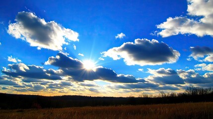 Wall Mural - bright white clouds scattered across a deep blue sky with rays of sunshine breaking through, creatin