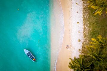 Drone view of two little kids playing in the sand and building a sand castle on a beautiful tropical beach near Grand Baie, Mauritius