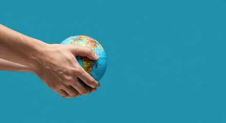 hands holding small globe against blue background