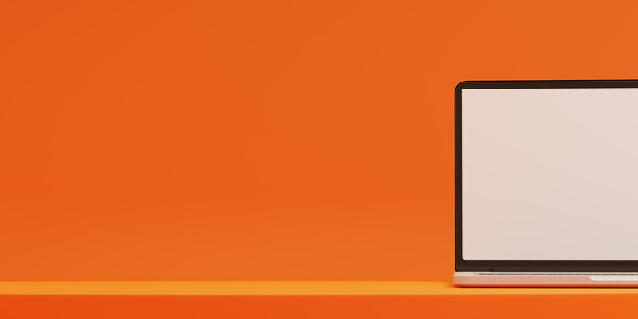 Laptop computer on an orange background with space for text