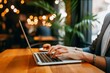 © Henhen - Person typing on a laptop in a cozy cafe with bokeh lights in the background.