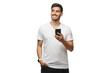 © Damir Khabirov - Young man standing in white t-shirt holding smartphone in hand and looking away with dreamful smile