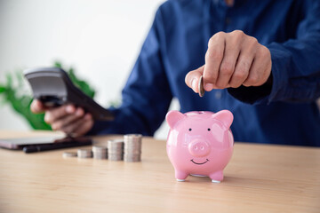 Man hand putting coins in pink piggy bank for account save money , Planning step up, saving money for future plan, retirement fund , Concept business finance saving money and investment.