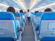 © niwat - Interior of airplane with passengers on seats and female traveler walking the aisle. Commercial economy flight service concept