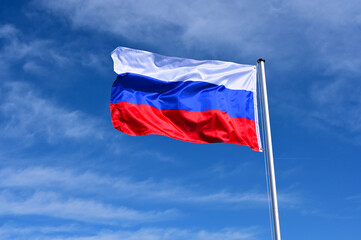 Wall Mural - The flag of Russia flutters in the wind against a blue cloudless sky