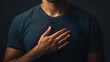 © Jittapon - A person standing solemnly with their hand placed over their heart making a symbolic gesture of a pledge promise or solemn commitment  This image conveys the concepts of allegiance integrity