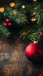 © Maria Mikhaylichenko - Festive Christmas scene with a shiny red ornament and pine branches on rustic wooden surface, illuminated by warm glowing lights creating a cozy atmosphere.