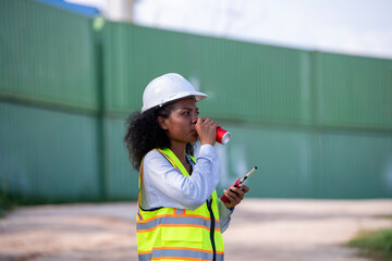 Engineer or dockworker working in the construction container dock yard checking and inspection containers drinking water environment is container shipping Logistics business concept.