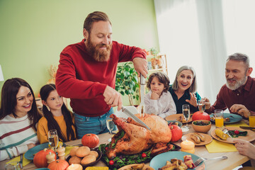 Poster - Photo of nice handsome man celebrating thanksgiving day together man cutting main traditional dish baked turkey indoors