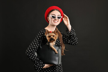 Sticker - Woman in sunglasses holding bag with cute Yorkshire Terrier dog on black background