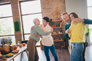 Wall Mural - Photo of cheerful family meeting hugging each other eating thanksgiving holiday dinner good mood having fun at home indoors