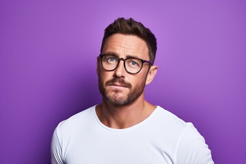 Portrait of a handsome young man in eyeglasses on a purple background.