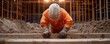 © WinThing - Construction worker wearing helmet and orange uniform at building site.