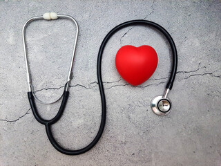 Heart with stethoscope on cracked cement surface. Top view.