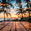 © Badass Prodigy - A serene sunset view with a wooden table in the foreground, surrounded by palm trees and decorative lights.