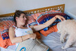 © Ana Luz Crespi/Stocksy - Woman with the flu is in bed with her dog