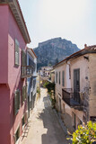 Fototapeta Uliczki - Experience the enchanting streets of Nafplio, where colorful traditional houses line the narrow lanes beneath a majestic mountain, creating a picturesque Greek view.