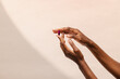© Nicole Mason/Stocksy - Hands Holding a Pill Against Neutral Background