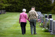 © Raymond Forbes LLC/Stocksy - Senior military Veteran holding wife hands walking Cemetery