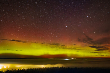 a vivid aurora borealis with striking red and green hues lights up the starry night sky above a town