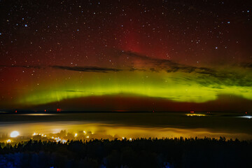 a vivid aurora borealis with striking red and green hues lights up the starry night sky above a town