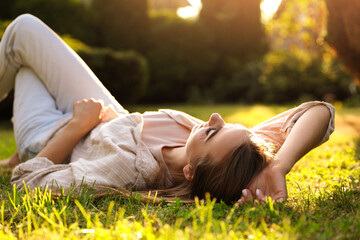 Canvas Print - Woman resting on green lawn in park