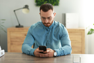 Poster - Handsome man looking at smartphone in office