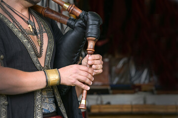 Hands of a musician playing the bagpipes made of leather and wood based on historical models at a medieval festival, copy space, selected focus