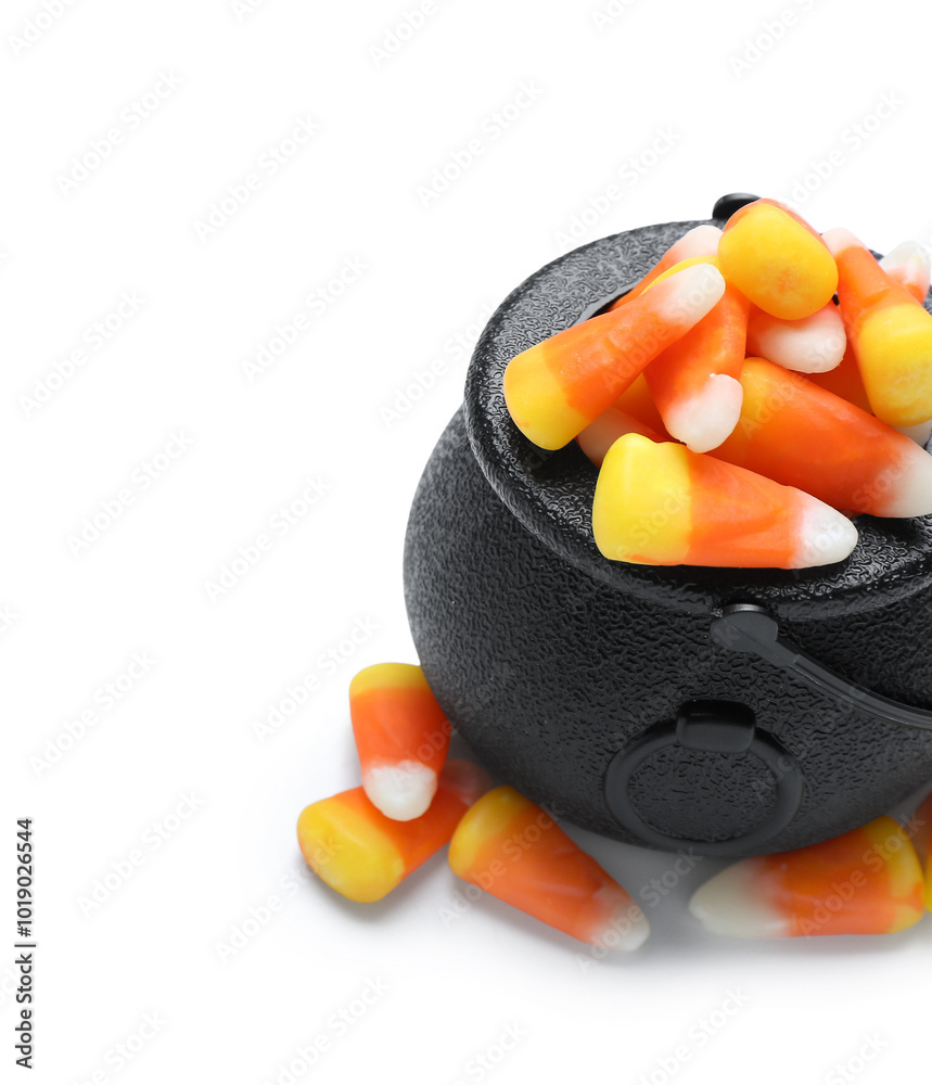 Cauldron with tasty Halloween candy corns on white background, closeup