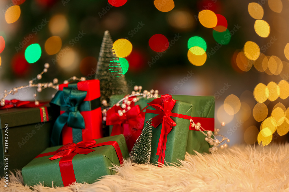 Different gift boxes on fur rug against blurred lights in living room, closeup