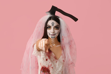 Canvas Print - Beautiful young woman dressed as dead bride for Halloween party with axe pointing at viewer on pink background