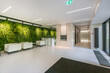 © alhim - Amazing design of an office hall in a modern building. The wall is decorated with green .plants. White tables and armchairs.