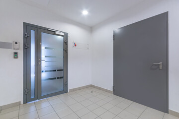 A corridor in a modern office with a light decor. Glass and gray doors.