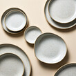 © homydesign - Minimalist ceramic plates arranged neatly on a beige surface