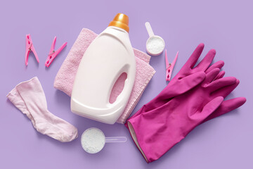 Wall Mural - Laundry detergents with clothespins, baby socks, towel and rubber gloves on purple background