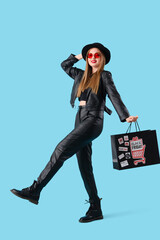 Wall Mural - Beautiful young happy woman with shopping bag on blue background. Black Friday sale