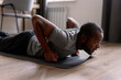 © Oleksii Syrotkin/Stocksy - Focused adult black man doing workout exercise on fitness mat at home