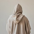 © Morng - Person in a beige hoodie facing away, minimalist and casual fashion concept, simple background.