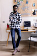 © Oleksii Syrotkin/Stocksy - Young black man with crossed arms looking at camera standing at desk