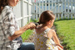 © Danil Nevsky/Stocksy - Close-up of mother braiding daughter's hair outdoors