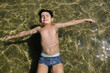 © VICTOR TORRES/Stocksy - Young boy floating in clear water with relaxed expression