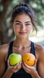 © Hryhor Denys - A young woman stands outdoors, holding a green apple in one hand and an orange in the other, smiling naturally and enjoying the vibrant fruits under soft sunlight