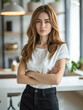 © romanets_v - Portrait of a young professional woman in a black shirt with arms crossed, standing in a modern office environment. Concept of business, professionalism, and confidence