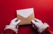 © adobestocker1 - Close-up of an open brown envelope being pulled out from between the fingers of Santa Claus.