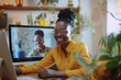 © Victor Bertrand - A smiling woman at her computer, engaging in a video call with a counterpart on the screen, surrounded by cozy home decor.