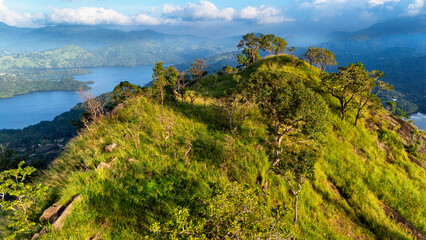 Sri Lanka's lush hills by calm waters. The picturesque hills of Sri Lanka rise above serene lakes, offering breathtaking views of nature in vibrant green hues.