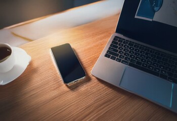 Fototapete - A smartphone and a laptop computer lie on a wooden surface with a cup of coffee.