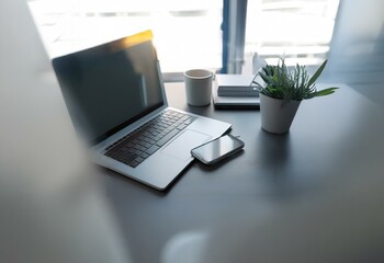 Poster - A desk with a laptop, phone, potted plant and a cup.