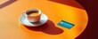 © Georgii - Bright orange table with a white cup of coffee and a credit card in a modern café setting