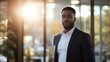 © Daniel - portrait of confident black business man standing in a modern office, looking at the camera